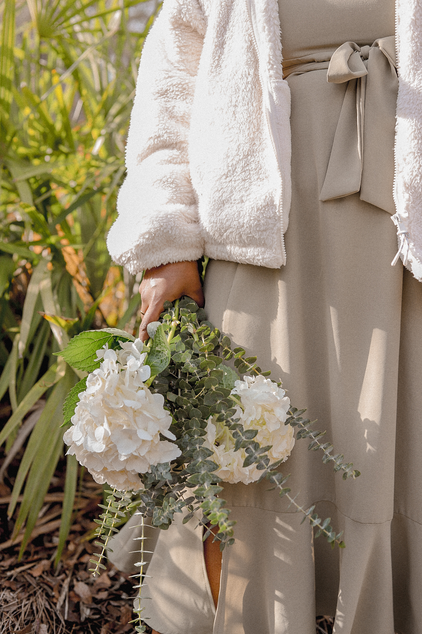 girl in white coat holding white flowers