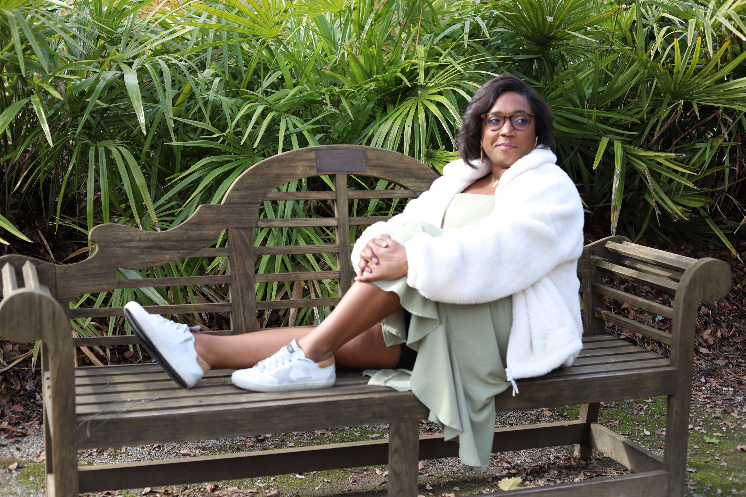 marketing freedom, sitting on a bench in a green dress outside with feet up